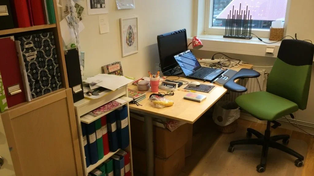 Kontorsarbetsplats med dator, pärmar och administrativt material