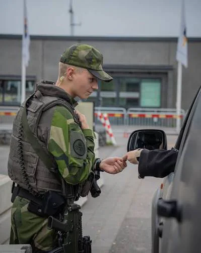 En uniformerad person kontrollerar en legitimation vid ett fordon